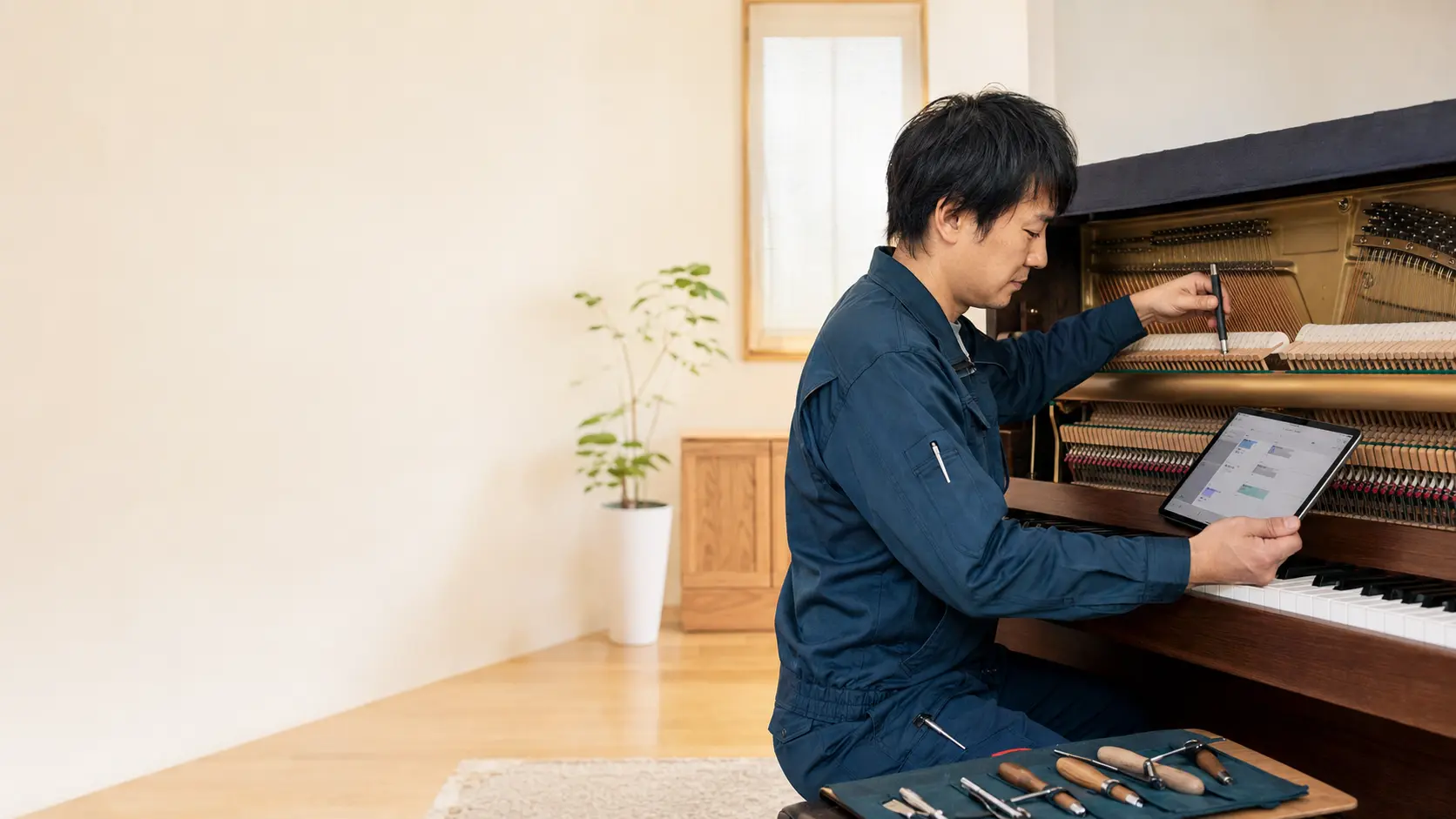 調律作業をしながらタブレットで訪問記録を確認する調律師